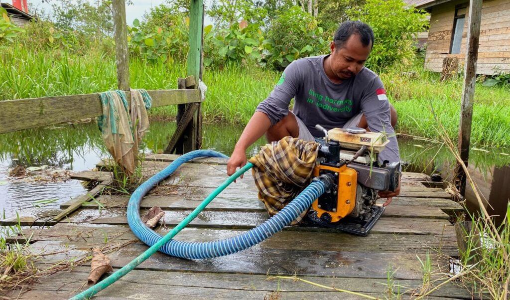 Hengki (23) mengoperasikan alat sedot air yang dialirkan ke rumah dari air sungai Sekonyer untuk MCK (mandi, cuci, kasus).
